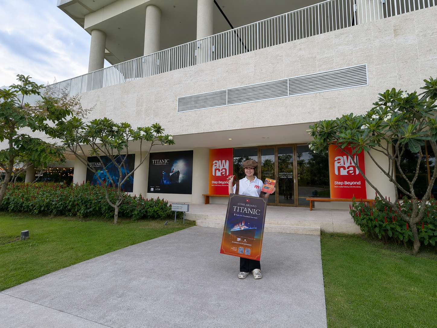 The Awra building entrance at Alma Resort Cam Ranh, with Titanic posters and a host holding a sign